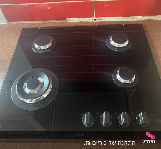 כיריים גז שחורות עם ארבעה מבערים וכפתורי שליטה